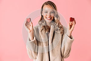 Beautiful happy young pretty woman posing isolated over pink wall background holding hearts