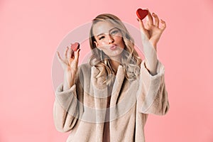 Beautiful happy young pretty woman posing isolated over pink wall background holding hearts