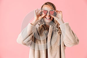 Beautiful happy young pretty woman posing isolated over pink wall background holding hearts