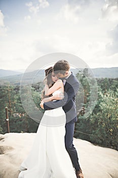 Beautiful happy young wedding couple posing on a background of rock cliff