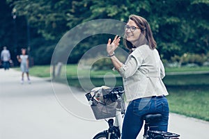 Beautiful happy young woman on bike in park