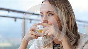 Beautiful happy young woman drinks tea at the cafe in the morning.