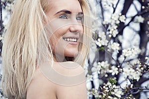 Beautiful happy young woman enjoying smell in a flowering spring