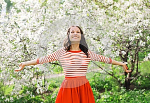 Beautiful happy young woman enjoying smell in a flowering spring