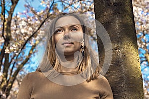 Beautiful happy young woman enjoying smell in a flowering spring