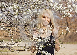 Beautiful happy young woman enjoying smell in a flowering spring garden