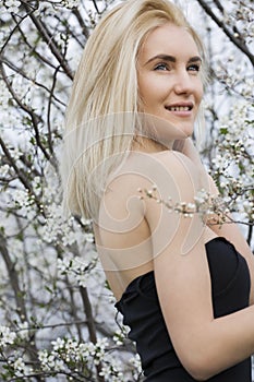 Beautiful happy young woman enjoying smell in a flowering spring garden