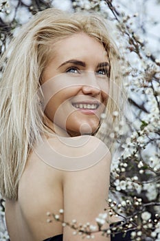 Beautiful happy young woman enjoying smell in a flowering spring garden