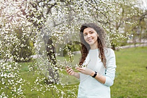 Beautiful happy young woman enjoying smell in a flowering spring garden