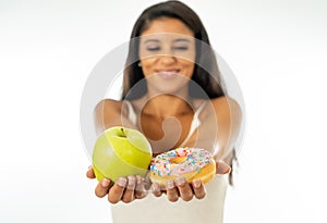 Attractive young woman on a diet deciding between an apple and a doughnut