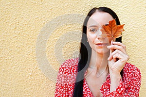 Beautiful happy young woman holding autumn leaves. girl outdoors in red dress