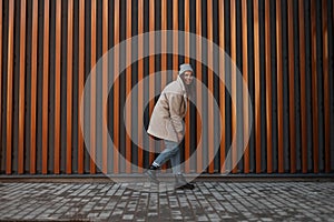 Beautiful happy young woman with a positive smile in a fashionable faux fur coat in stylish jeans in a knitted hat in leather