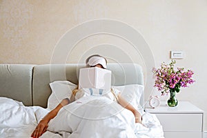 Beautiful Happy Young Woman sleeping with notebook In Bed. Portrait Of stlish Blonde Girl with blindfold in bedroom