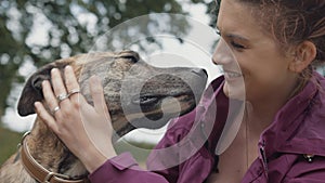 Beautiful Happy Young Woman Stroking her Loving & Loyal Pet Dog in Park