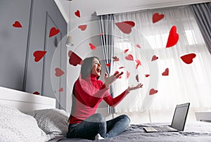 Beautiful, happy, young woman throwing red heart-shapes in the air