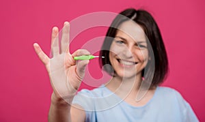 Beautiful happy young woman using interdental brush on the pink background