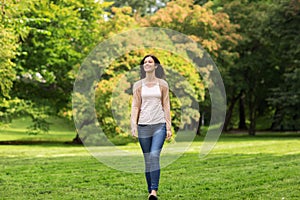Beautiful happy young woman walking in summer park