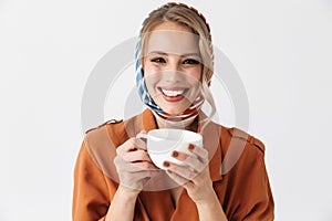 Beautiful happy young woman wearing silk scarf isolated over white background drinking coffee or tea