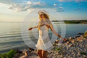 Beautiful happy young woman in white summer satin dress whirls a