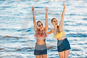 beautiful happy young women raising hands and having fun together