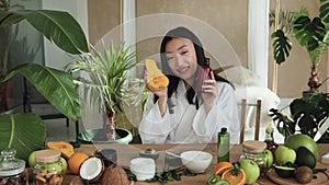 Beautiful healthy asian woman holding pumpkin and bottle with body milk or cream