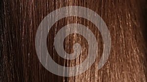 Beautiful healthy brown Hair. A closeup view of a bunch of shiny straight brown hair in a wavy style. slow motion smooth