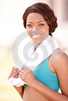 Beautiful and healthy. A pretty african-american woman in sportswear with a towel around her neck.