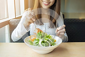 Beautiful healthy woman is holding vegetables salad