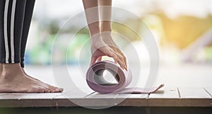 Beautiful Healthy woman rolling yoga mattress after doing yoga beside a swimming pool. Relaxation happiness Healthcare concept