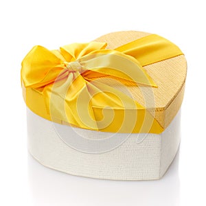 Beautiful heart shaped gift box with big yellow bow. Isolated. Side view