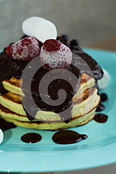 Beautiful hearty breakfast of puncakes with hot chocolate, berries, strawberries and marshmellows.