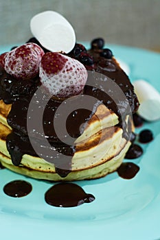 Beautiful hearty breakfast of puncakes with hot chocolate, berries, strawberries and marshmellows.