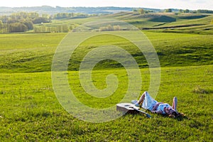 Beautiful hippie girl with guitar lying on grass