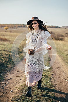 Beautiful hippie girl in hat walking on road in nature