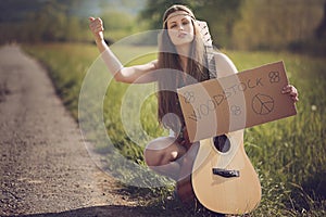 Beautiful hippie with guitar hitch-hiking