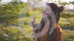 Beautiful hippie woman with dreadlocks in the woods at sunset having good time outdoors