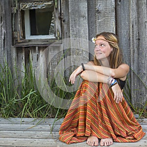 Beautiful hippies girl sitting outdoors in the countryside, looking blank space on the left.