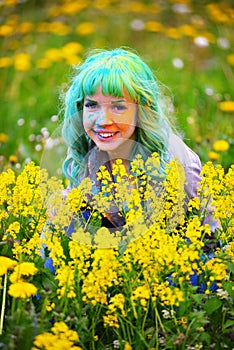 Beautiful hipster alternative young woman with green hair sits in grass with dandelion in park