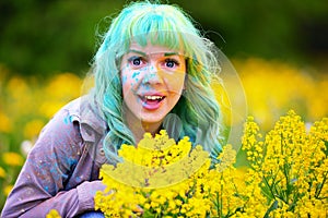 Beautiful hipster alternative young woman with green hair sits in grass with dandelion in park