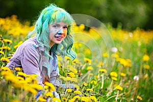 Beautiful hipster alternative young woman with green hair sits in grass with dandelion in park