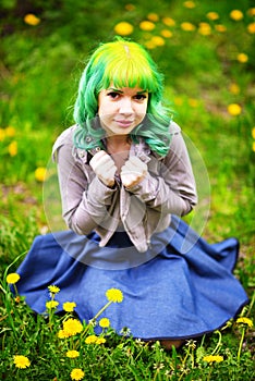 Beautiful hipster alternative young woman with yellow hair sits in grass with dandelion in park