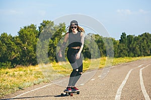A beautiful, hipster blonde with blue hair in tattoo ride a longboard