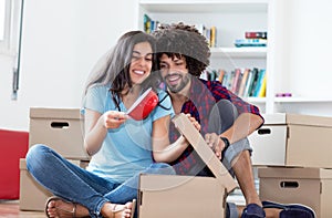 Beautiful hipster couple unpacking boxes in new home