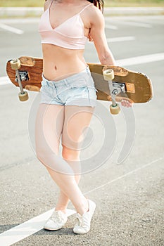 Beautiful, hipster stands with a longboard it is turned back on the street.