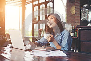 Beautiful hipster woman using laptop at cafe while drinking coffee, Relaxing holiday concept.