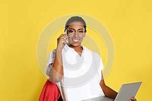 Beautiful Hispanic businesswoman with laptop and smartphone sitting on chair