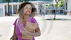 Beautiful hispanic female student with backpack infront of university