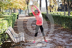 Beautiful hispanic sport woman in sportswear stretching body next to bench doing flexibility exercises warm up