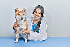 Beautiful hispanic veterinarian woman checking dog health smiling with a happy and cool smile on face