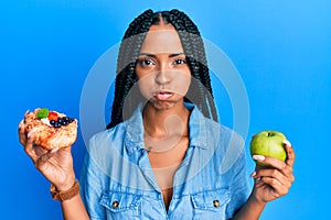 Bellissimo ispanico una donna possesso pasticcini un salutare verde mela facce ridicolo 